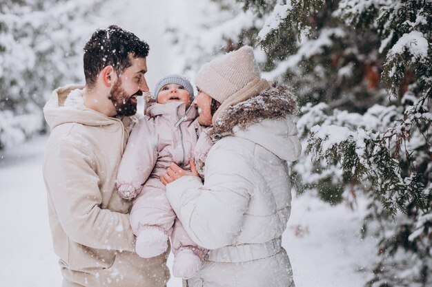 Giovane famiglia con la piccola figlia in una foresta di inverno piena di neve