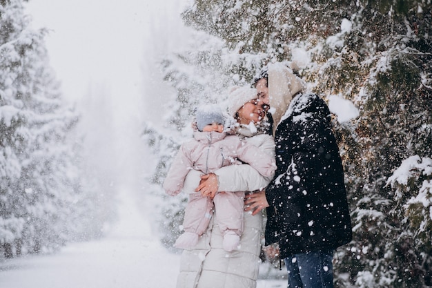 Giovane famiglia con la piccola figlia in una foresta di inverno piena di neve