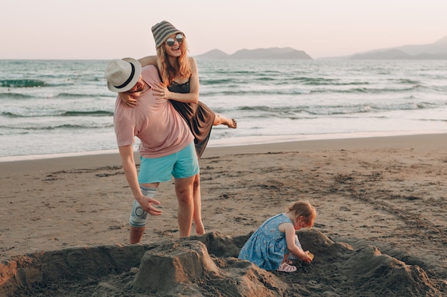 Giovane famiglia felice con il piccolo bambino che si diverte in spiaggia. Famiglia gioiosa.