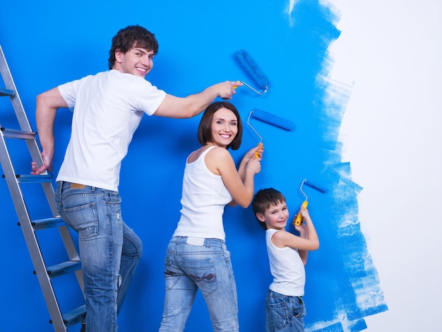 Giovane famiglia felice con il piccolo figlio che dipinge il muro