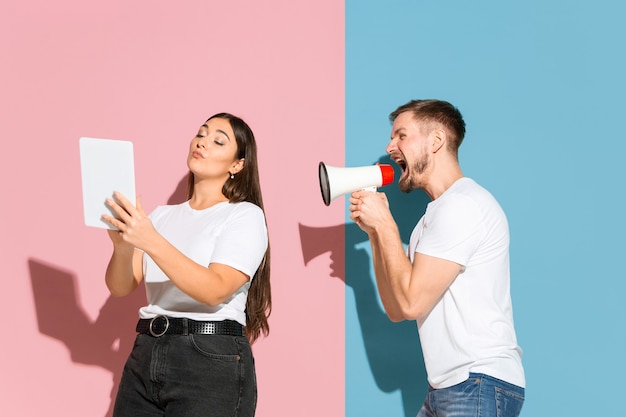 Giovane, felice uomo e donna in abiti casual su sfondo rosa, blu bicolore.