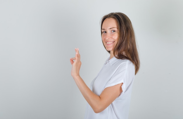 Giovane femmina che fa segno giusto in camicia bianca e che sembra soddisfatta.