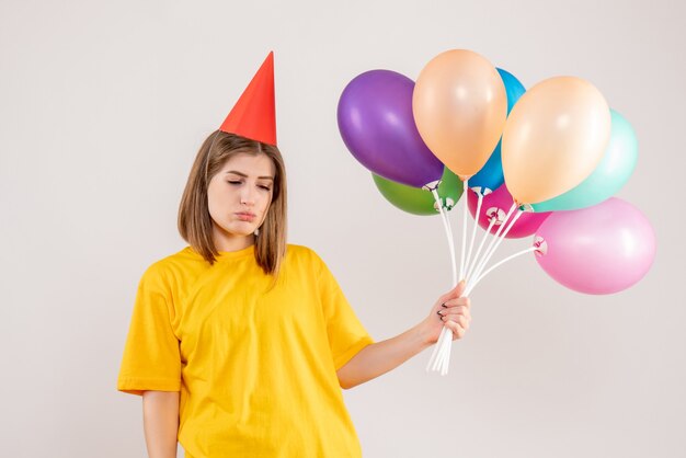 giovane femmina che tiene palloncini colorati su bianco