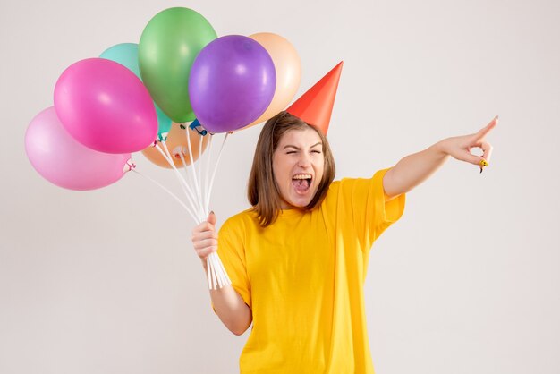 giovane femmina che tiene palloncini colorati su bianco