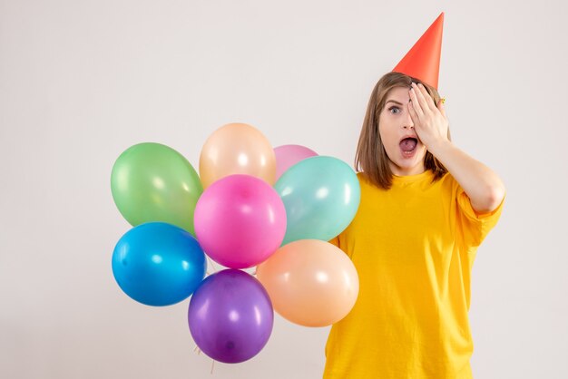 giovane femmina che tiene palloncini colorati su bianco