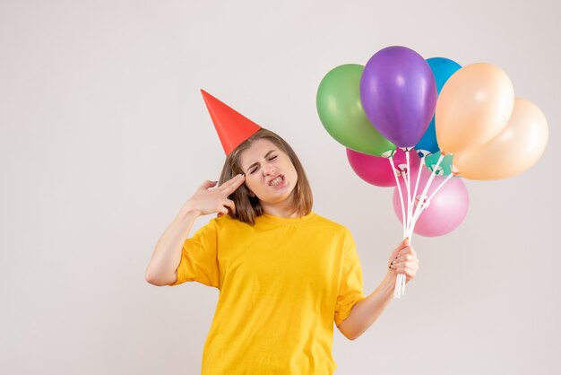 giovane femmina che tiene palloncini colorati su bianco