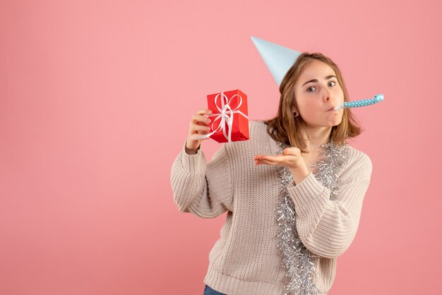 giovane femmina che tiene piccoli regali di Natale sul rosa