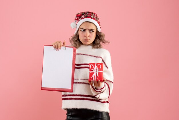 giovane femmina che tiene poco regalo di Natale e nota sul rosa