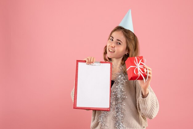 giovane femmina che tiene poco regalo di Natale e nota sul rosa