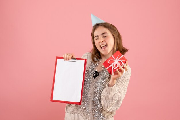 giovane femmina che tiene poco regalo di Natale e nota sul rosa