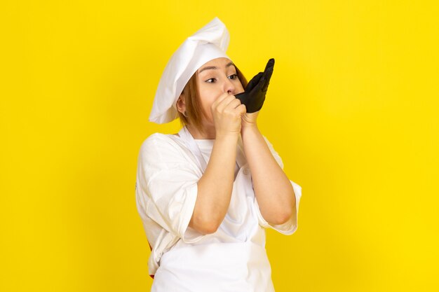 giovane femmina di cucina in abito bianco cuoco e berretto bianco che indossa un guanto nero