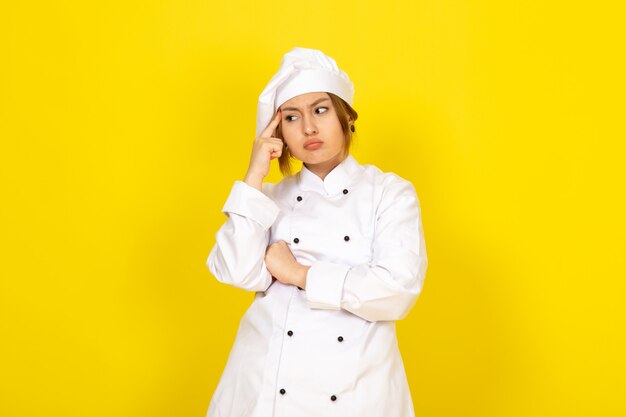 giovane femmina di cucina in abito bianco cuoco e berretto bianco espressione di pensiero