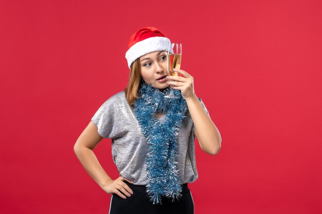 Giovane femmina di vista frontale che celebra il nuovo anno sul colore rosso di festa di natale della parete