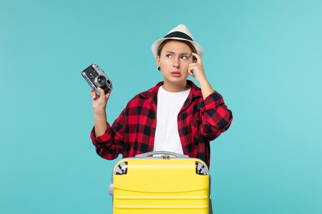 Giovane femmina di vista frontale che prepara per la vacanza e che tiene macchina fotografica della foto sullo spazio blu