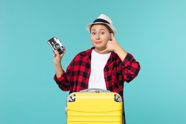 Giovane femmina di vista frontale che prepara per la vacanza e che tiene macchina fotografica sullo spazio blu