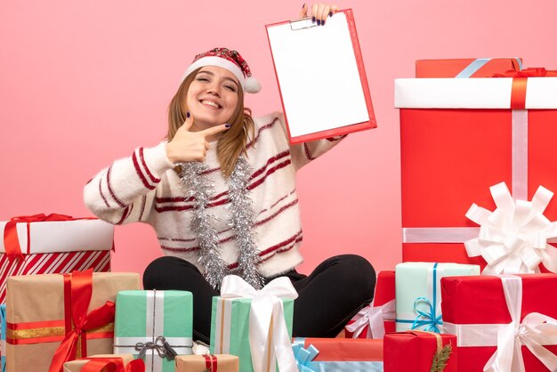 Giovane femmina di vista frontale che si siede intorno ai regali di natale con la nota dell'archivio