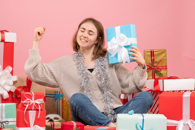 Giovane femmina di vista frontale che si siede intorno ai regali di natale differenti