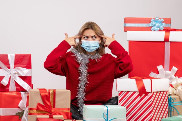 Giovane femmina di vista frontale che si siede intorno ai regali di Natale in maschera