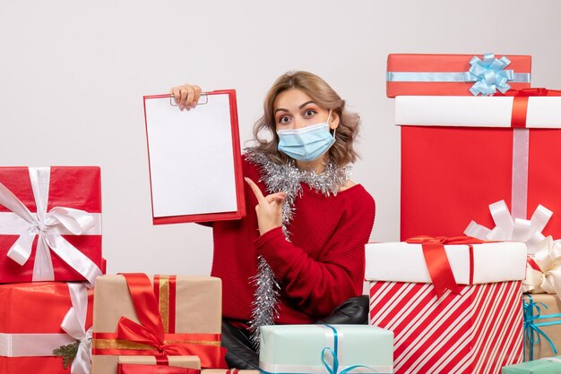 Giovane femmina di vista frontale che si siede intorno ai regali di Natale in maschera