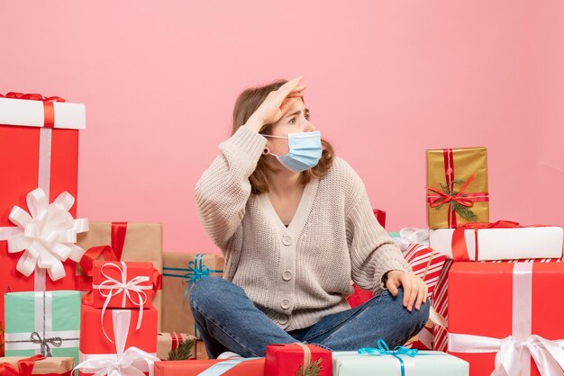 Giovane femmina di vista frontale che si siede intorno ai regali di natale in maschera