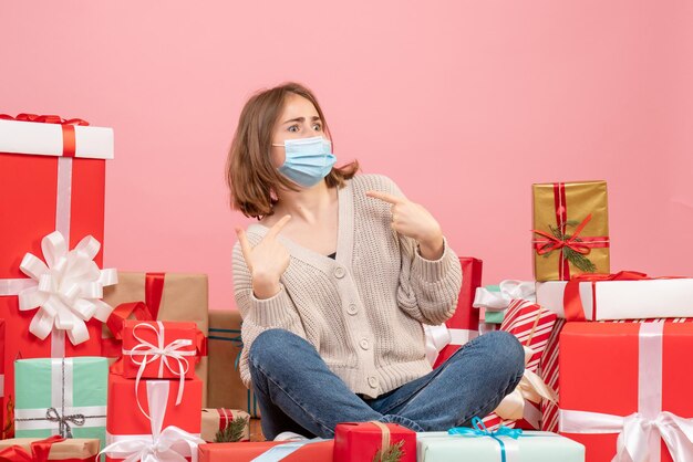 Giovane femmina di vista frontale che si siede intorno ai regali di natale in maschera