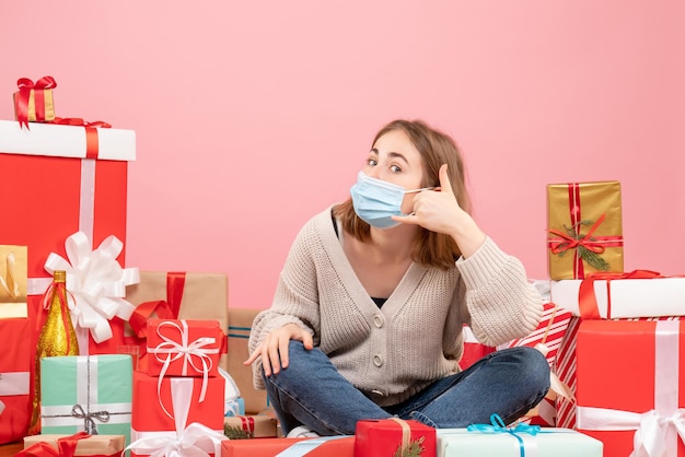 Giovane femmina di vista frontale che si siede intorno ai regali di natale nella maschera sterile