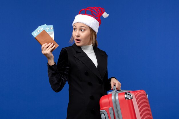 Giovane femmina di vista frontale che tiene i biglietti con la borsa sulle vacanze di vacanza della donna del fondo blu