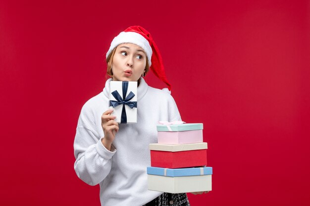 Giovane femmina di vista frontale che tiene i regali del nuovo anno sullo scrittorio rosso