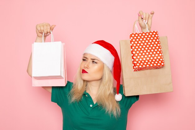 Giovane femmina di vista frontale che tiene i regali di Natale in pacchetti sulle vacanze di capodanno del modello della foto di natale della parete rosa