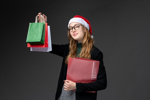 Giovane femmina di vista frontale con i pacchetti sul regalo di Natale del nuovo anno del regalo scuro della parete