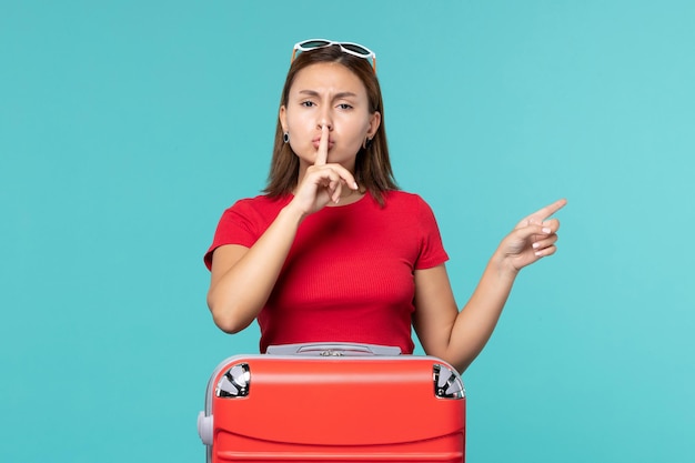 Giovane femmina di vista frontale con il sacchetto rosso che prepara per la vacanza sullo spazio blu-chiaro