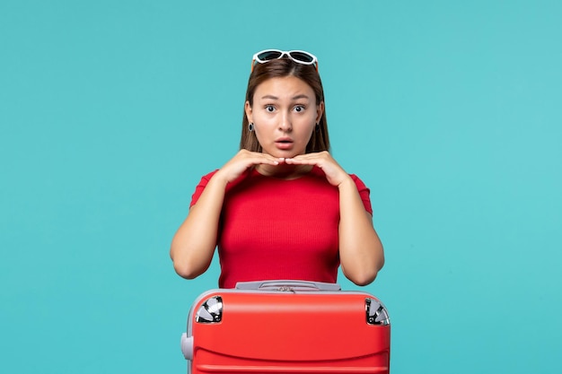 Giovane femmina di vista frontale con il sacchetto rosso che si prepara per la vacanza sullo spazio blu
