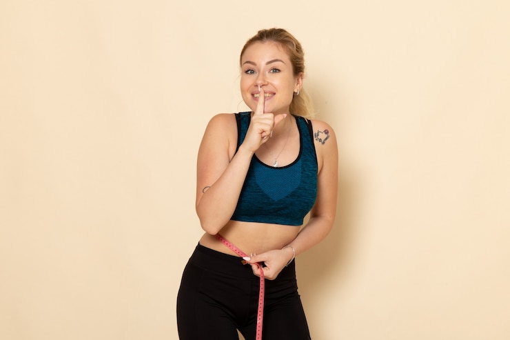 Foto gratuito giovane femmina di vista frontale in attrezzatura di sport che misura il suo corpo
