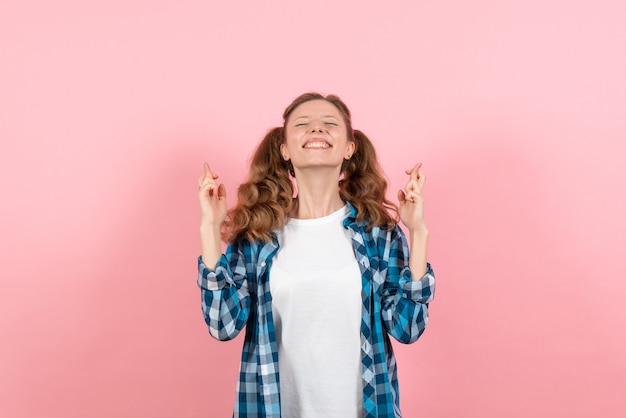 Giovane femmina di vista frontale in camicia a scacchi in posa e incrocio le dita sullo sfondo rosa modello del bambino di emozioni di colore della gioventù della donna