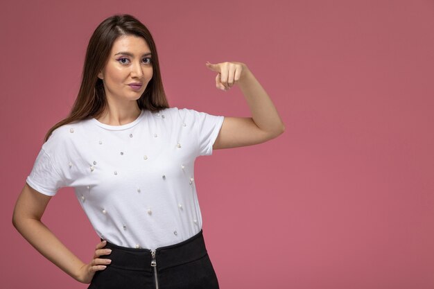 Giovane femmina di vista frontale in camicia bianca che sorride leggermente sulla parete rosa