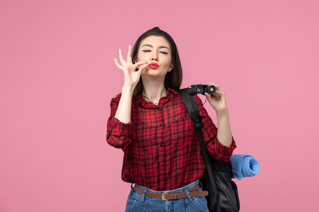 Giovane femmina di vista frontale in camicia rossa con il binocolo sulla donna di colore di moda sfondo rosa