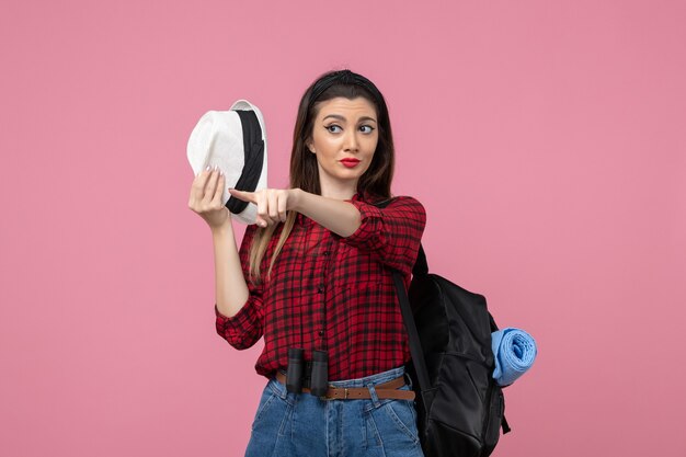 Giovane femmina di vista frontale in camicia rossa con il cappello sulla donna umana di colore di sfondo rosa