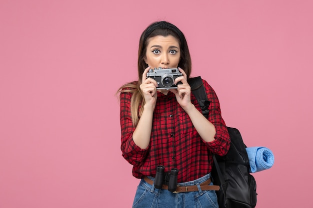 Giovane femmina di vista frontale in camicia rossa con la macchina fotografica sulla donna rosa della foto del modello del fondo