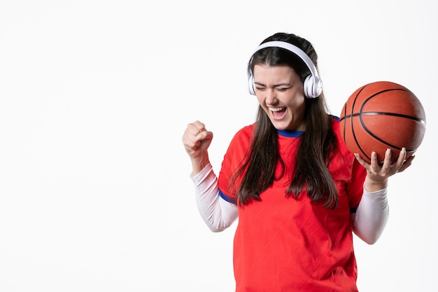 Giovane femmina di vista frontale in vestiti di sport con muro bianco di basket