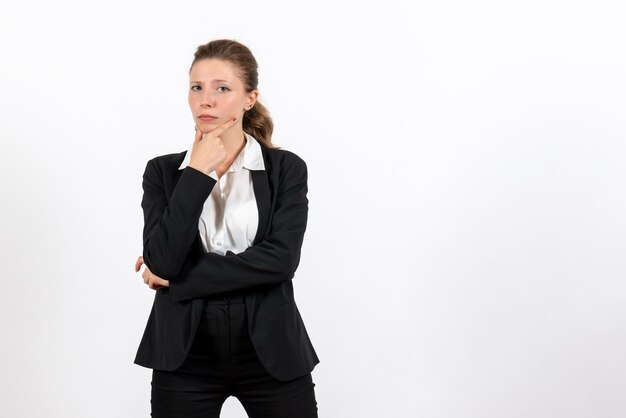 Giovane femmina di vista frontale in vestito classico rigoroso che posa e che pensa sul lavoro femminile del lavoro del lavoro della donna di affari del fondo bianco