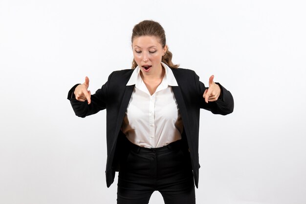 Giovane femmina di vista frontale in vestito classico rigoroso che posa sul lavoro femminile di lavoro di lavoro della donna del costume del fondo bianco