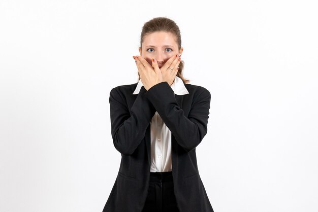 Giovane femmina di vista frontale in vestito classico rigoroso che posa sul vestito di lavoro femminile del lavoro della donna di affari del fondo bianco