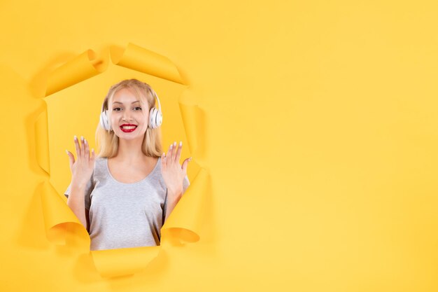 Giovane femmina in cuffie su carta gialla strappata audio di sottofondo musicale