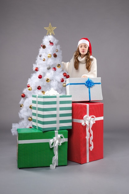 giovane femmina intorno a regali di Natale su grigio