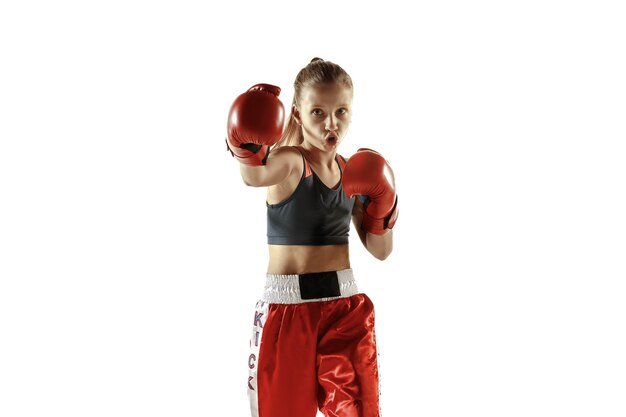 Giovane femmina kickboxing fighter training isolato sul muro bianco. Ragazza bionda caucasica in abiti sportivi rossi che praticano nelle arti marziali. Concetto di sport, stile di vita sano, movimento, azione, gioventù.