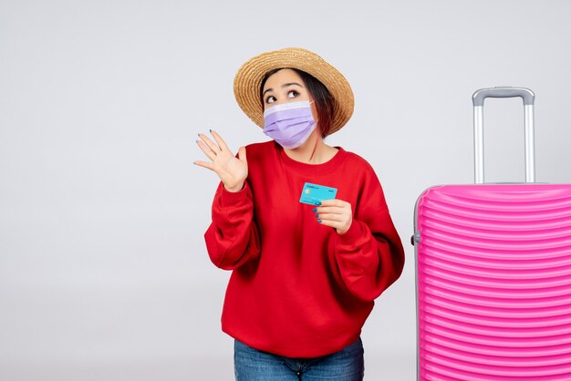 Giovane femmina vista frontale che si prepara per il viaggio in maschera sul muro bianco