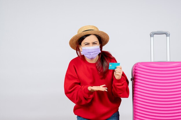 Giovane femmina vista frontale che si prepara per il viaggio in maschera sul muro bianco