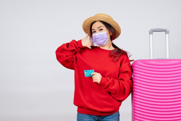 Giovane femmina vista frontale che si prepara per il viaggio in maschera sul muro bianco