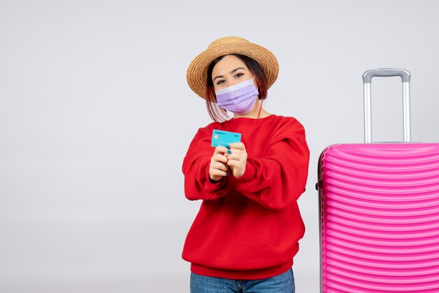 Giovane femmina vista frontale che si prepara per il viaggio in maschera sul muro bianco