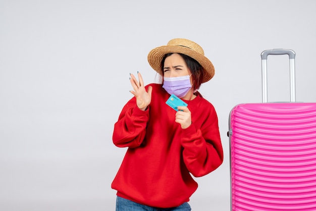 Giovane femmina vista frontale che si prepara per il viaggio in maschera sul muro bianco